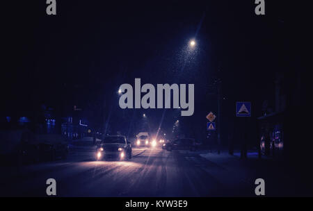 La neige est tombée dans la ville, une situation difficile dans la rue, les voitures passent lentement avec beaucoup de prudence, la scène de nuit. Banque D'Images