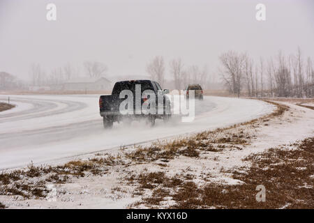 Les véhicules qui circulent sur route glacée glissante dans une tempête de neige. Banque D'Images