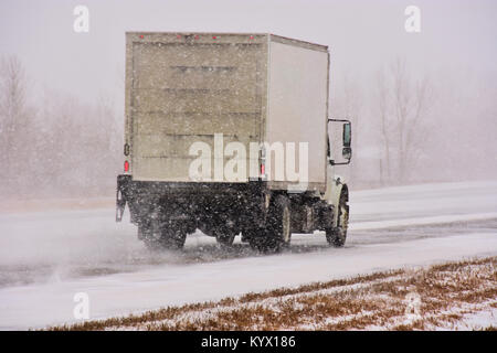 Les véhicules qui circulent sur route glacée glissante dans une tempête de neige. Banque D'Images