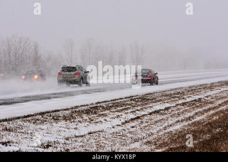 Les véhicules qui circulent sur route glacée glissante dans une tempête de neige. Banque D'Images