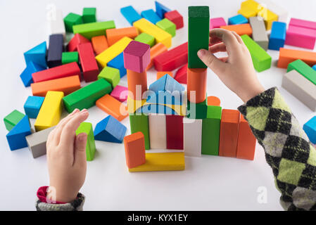 Quatre ans fille joue dans le concepteur. Jouets en bois colorés, children's designer sur fond blanc, de divertissement avec un enfant, le développement de prés Banque D'Images