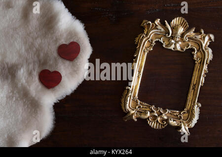 Or antiq photo frame dans un style rococo, sur fond de bois rustique foncé avec du blanc mouton de Toscane et les cœurs Banque D'Images