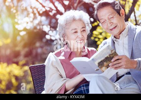 Le vieux couple heureux lire au soleil Banque D'Images