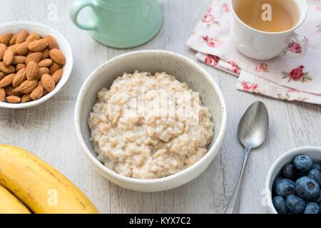 L'avoine, l'avoine porridge écossais ou gruau servi avec des noix, des fruits, des baies et du thé vert. Un petit-déjeuner sain, un régime amaigrissant, l'alimentation saine notion Banque D'Images