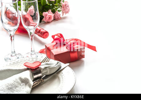 Valentines Day le dîner avec table place setting with red gift, verre de champagne, des ornements du cœur avec l'argenterie sur fond blanc. Close up. Vale Banque D'Images
