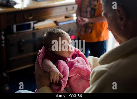 Un grand-père tient sa petite-fille de deux mois dans une couverture rose. Banque D'Images