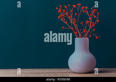 Petit Bouquet de fleurs dans Vase Vintage rouge sur la table en bois bleu marine fond mur. Image style de maquette d'art texte cite des toiles lettrage Banque D'Images