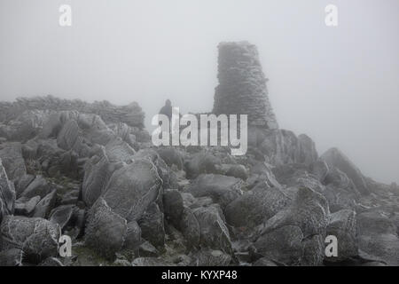 Walker est entourée de rochers couverts de givre blanc Le givre blanc (Disque) sur le sommet du rocher de Thornthwaite dans le Parc National du Lake District, Cumbria, Royaume-Uni. Banque D'Images