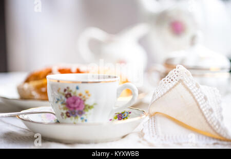 Bateau à thé en porcelaine avec une tasse, théière, bol de sucre sur le gâteau spongieux avec nappe blanche sur une plaque Banque D'Images