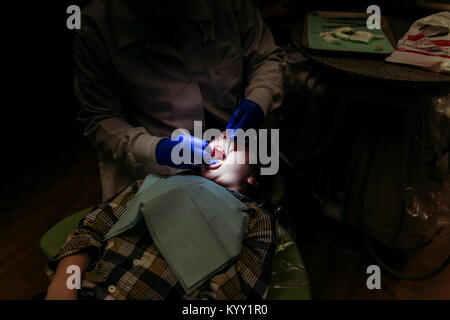 Portrait de dentiste examining patient en chambre noire Banque D'Images