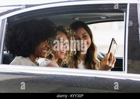 Cheerful businesswomen en tenant avec selfies smart phone in car vu à travers la vitre Banque D'Images