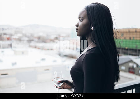 Vue latérale d'une businesswoman holding verre en regardant ailleurs dans l'hôtel Balcony Banque D'Images