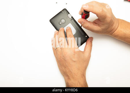 L'homme de faire des ajustements et des réparations à son smartphone à l'aide d'un tournevis de précision dans une vue en gros plan de ses mains et l'démonté sur téléphone mobile Banque D'Images
