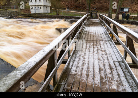 Morrum, Suède - 8 janvier 2018 : Documentaire de la vie quotidienne et de l'environnement. Un très glissantes et glacées pont de bois sur une rivière déchaînée durant les crues Banque D'Images