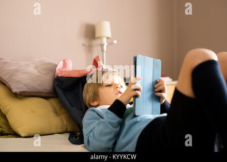 Boy using digital tablet dans la chambre à coucher dans la chambre à coucher Banque D'Images