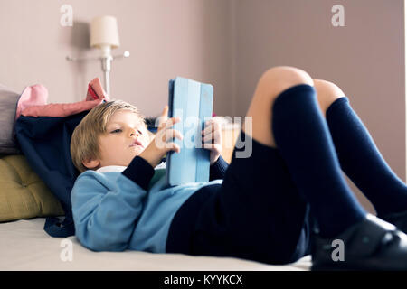 Boy using digital tablet dans la chambre à coucher dans la chambre à coucher Banque D'Images