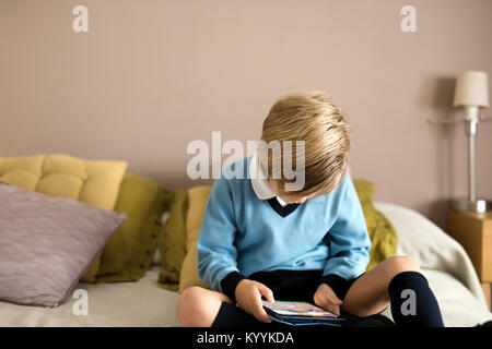 Boy using digital tablet dans la chambre à coucher dans la chambre à coucher Banque D'Images