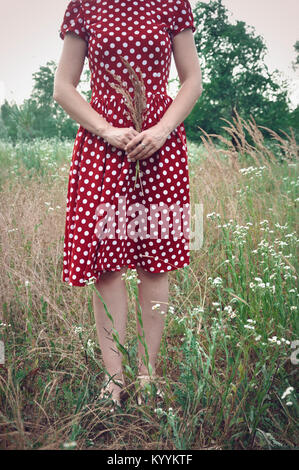 Femme en robe rouge standing in field Banque D'Images