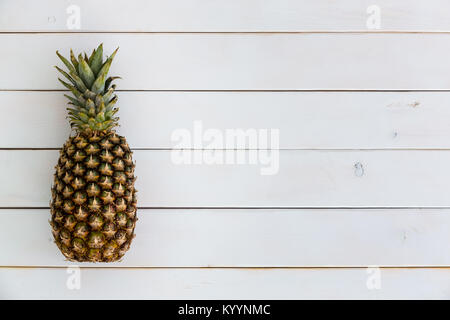 Ananas frais fruit tropical avec sa couronne de feuilles comme une frontière latérale sur un fond de bois blanc with copy space Banque D'Images