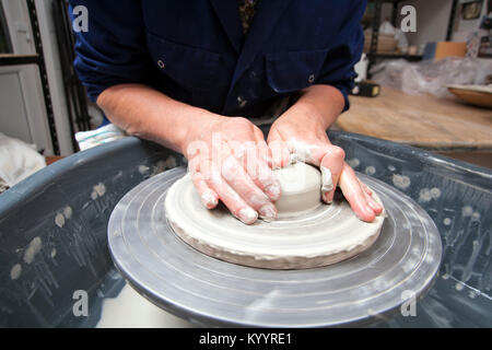 Une dame de la céramique artiste à l'œuvre dans son home studio de poterie, une tasse de centrage Banque D'Images