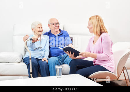 Jeune femme bénévole lit des histoires à partir d'un répertoire pour les aînés Banque D'Images