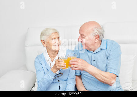 Professionnels Seniors couple toasting avec du jus d'orange à la maison ou en maison de retraite Banque D'Images