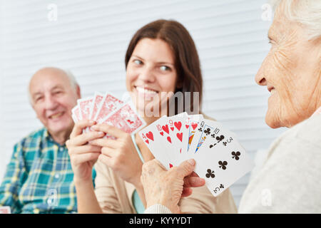 Petite-fille joue aux cartes avec les grands-parents dans la maison de soins infirmiers ou à la maison Banque D'Images