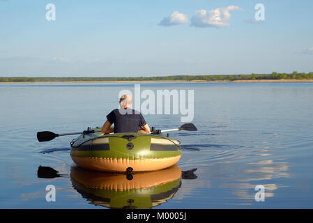 L'homme dans un bateau gonflable flotte sur la rivière, la vue de l'arrière Banque D'Images