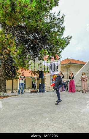 Arsos Village, Chypre - Octobre 8, 2017 : l'homme habillé en costume traditionnel de danse folklorique, thrapani holdng, une faux, à un festival. Banque D'Images