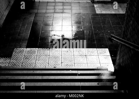 Les étapes d'un sombre tunnel de la station avec les flaques et les murs humides. Banque D'Images