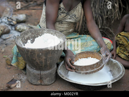 Réserve forestière de DZANGA-SANHA, Afrique. Le Central-African Republс de jungle. Femme Baka cuit les aliments, à l'écrasement d'une farine dans un mortier Banque D'Images