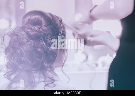 Fille méconnaissable de nouveau à nous, fille en miroir à faire coiffure coiffure, coiffure de cheveux longs, coiffure, partiellement visible mains maître. Floue, tonique Banque D'Images