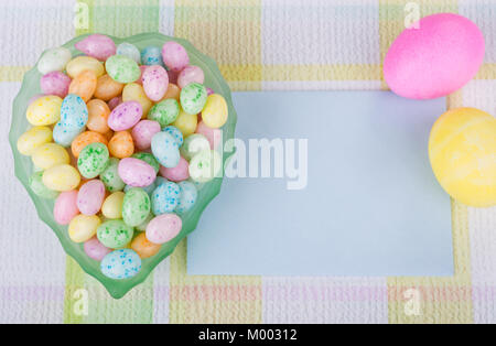 Bonbons de Pâques dans un bol avec les oeufs colorés et enveloppe vierge Banque D'Images