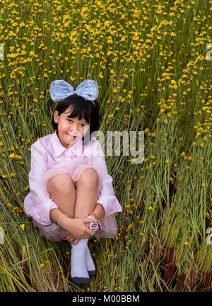 Asian cute little girl dans champ de fleurs jaunes Banque D'Images