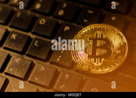 Coin bitcoin or sur noir clavier avec fuite de lumière Banque D'Images