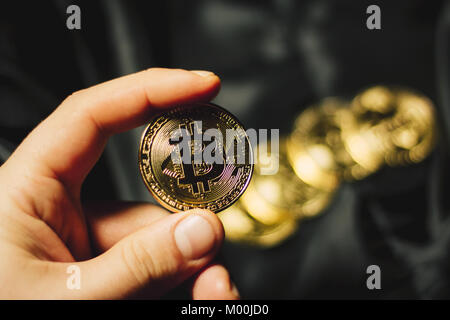 Man hand holding coin Bitcoin avec quelques pièces d'or en arrière-plan Banque D'Images