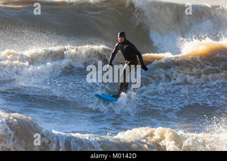 Hastings, East Sussex, UK. 18 janvier, 2018. Le soleil brille mais c'est beaucoup de vent ici dans Hastings, la mer fait rage en dépit de la marée étant out, ces surfeurs de profiter de la mer difficile en utilisant le mur du port à mesure qu'il crée des vagues plus grandes lorsqu'ils montent à la côte. Crédit photo : Paul Lawrenson/Alamy Live News Banque D'Images