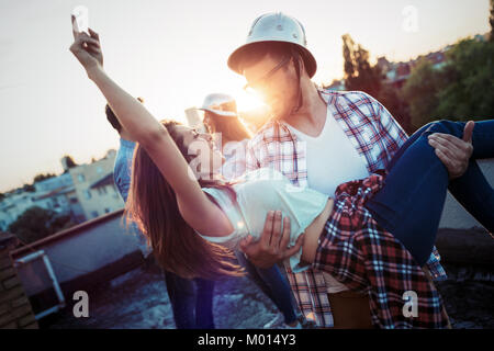 Couple flirting tout en prenant un verre sur la terrasse sur le toit Banque D'Images