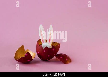 Concept de Pâques. Les oeufs colorés sur un fond rose, lapin de Pâques cache Banque D'Images