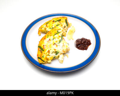 Une portion d'une Frittata faite avec des œufs et des légumes avec le chutney sur une plaque cerclée de bleu sur fond blanc Banque D'Images