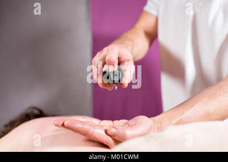 Close-up verse de l'huile dans la paume. Ostéopathe faire massage sur l'abdomen des femmes manipulatrices. Homme Femme massage mains.Thérapeute en appliquant une pression sur le ventre. Le concept de centre de spa Banque D'Images