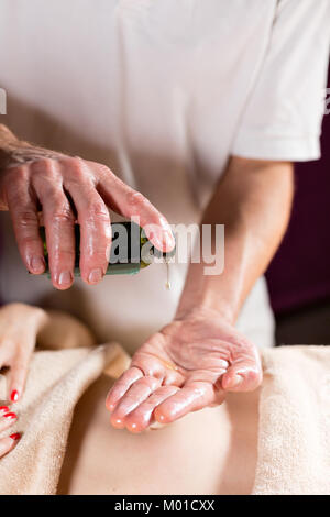 Close-up verse de l'huile dans la paume. Ostéopathe faire massage sur l'abdomen des femmes manipulatrices. Homme Femme massage mains.Thérapeute en appliquant une pression sur le ventre. Le concept de centre de spa Banque D'Images