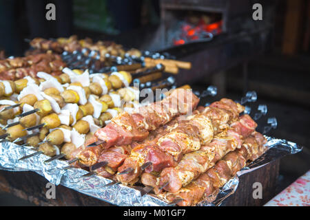 De nombreuses matières premières brochettes de viande de porc et de veau et de pommes de terre crues avec du bacon. Banque D'Images