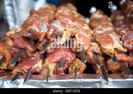 De nombreuses matières premières brochettes de viande de porc et de veau et de pommes de terre crues avec du bacon. À côté il y a une brochette de saucisses et des shish kebabs. Banque D'Images