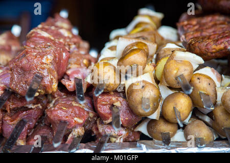 De nombreuses matières premières brochettes de viande de porc et de veau et de pommes de terre crues avec du bacon. À côté il y a une brochette de saucisses et des shish kebabs. Banque D'Images