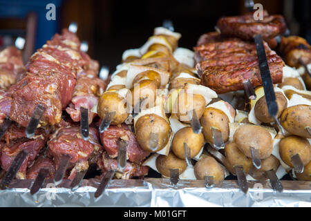 De nombreuses matières premières brochettes de viande de porc et de veau et de pommes de terre crues avec du bacon. À côté il y a une brochette de saucisses et des shish kebabs. Banque D'Images