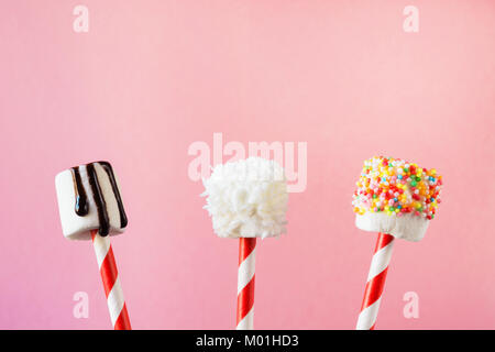 Sweet moelleux marshmallow et sucettes sur paille décoré avec du chocolat fondu et des gâteaux Sprinkles sur fond rose. Les enfants adoreront ces décisions. Cop Banque D'Images