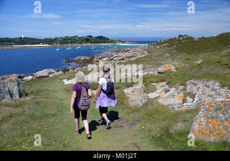 Deux femmes marchant sur Gugh vers (le bar) une plage de galets et sable le relie à St Agnes à marée basse dans les îles Scilly, l'Angleterre, Cornwall, UK. Banque D'Images