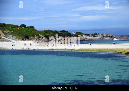 Les gens marcher à pied à travers (le bar) une plage de galets et de sable qui relie Gugh & St Agnes à marée basse dans les îles Scilly, l'Angleterre, Cornwall, UK. Banque D'Images