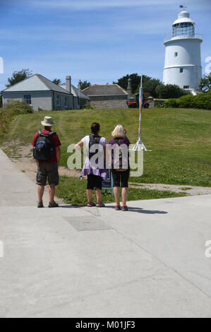 Trois touristes regardant le phare désaffecté blanc au centre de l'île de St Agnes, Penzance, Cornwall, Royaume-Uni. Banque D'Images